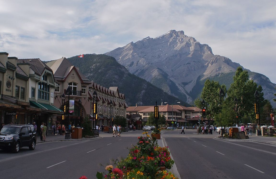 Banff Avenue in the mountain town of Banff, Alberta, with shops and peaks rising behind the main street