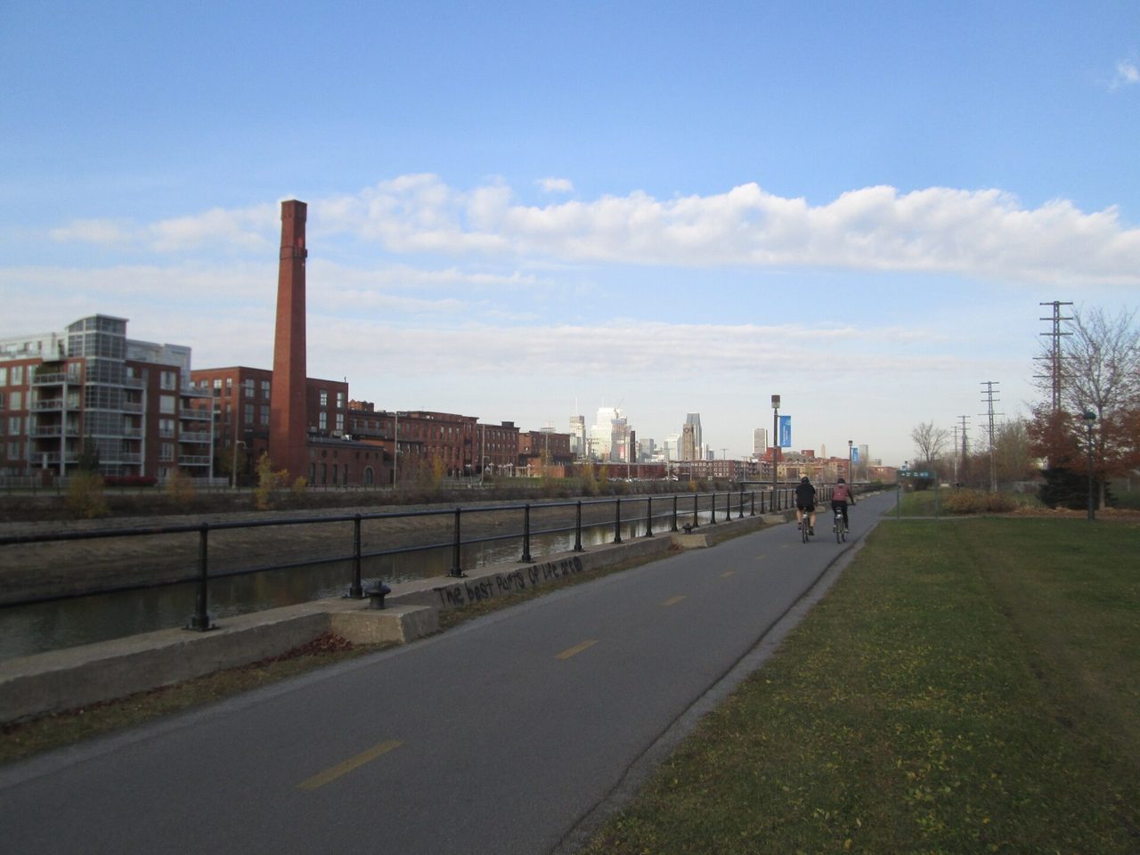 Cyclists riding along the tree-lined Lachine Canal path on a summer afternoon