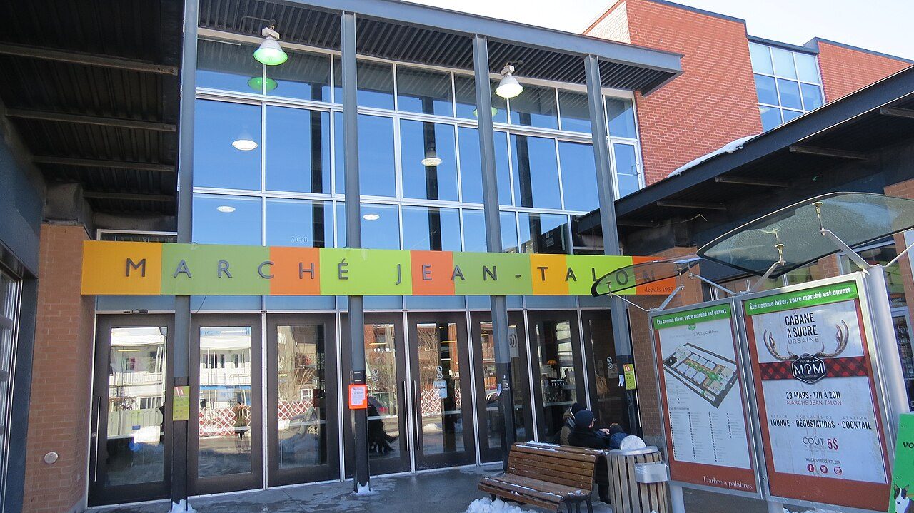 Colorful produce stalls and shoppers inside Marché Jean-Talon in Little Italy