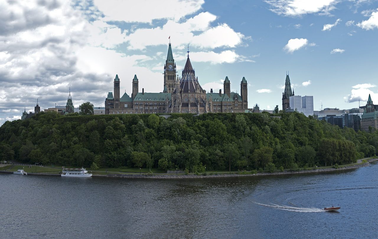 Parliament Hill's Gothic Revival buildings rising above the Ottawa River on a summer day