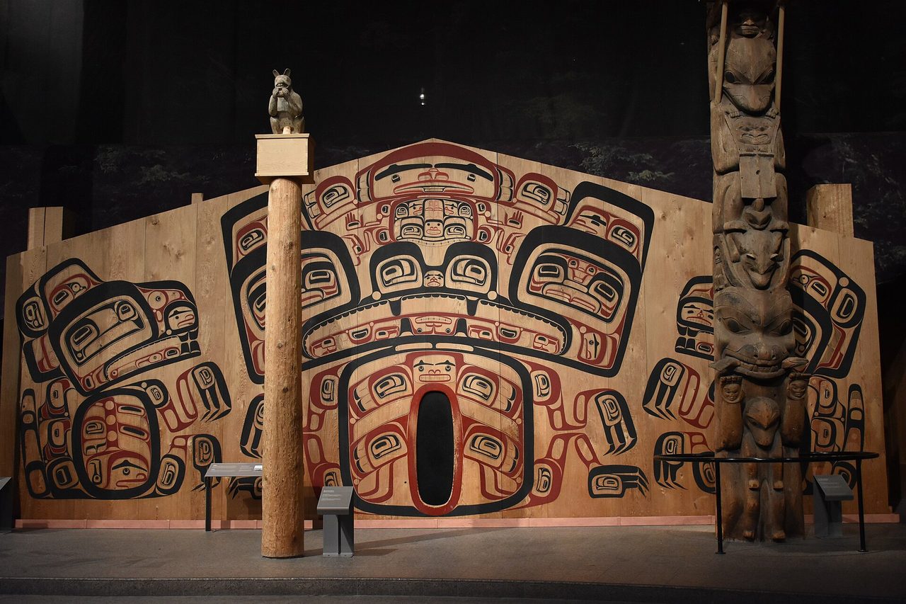 A painted wooden house facade and carved totem pole in the First Peoples Hall of the Canadian Museum of History