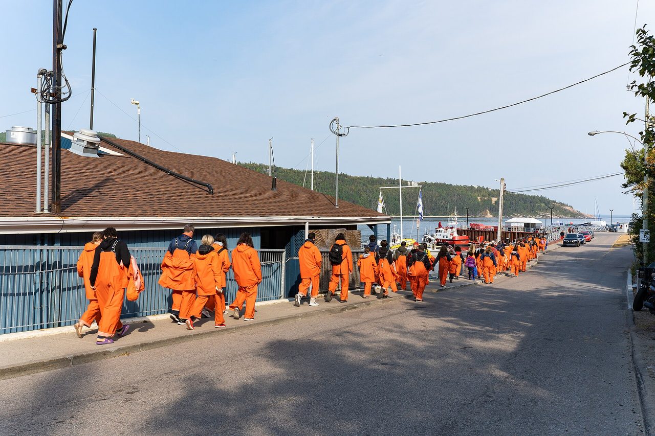 Whale-watchers in orange flotation suits boarding a zodiac at Tadoussac