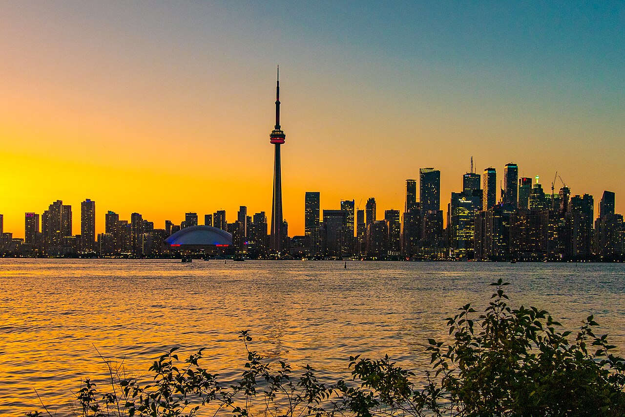 Toronto skyline and CN Tower glowing at sunset over Lake Ontario