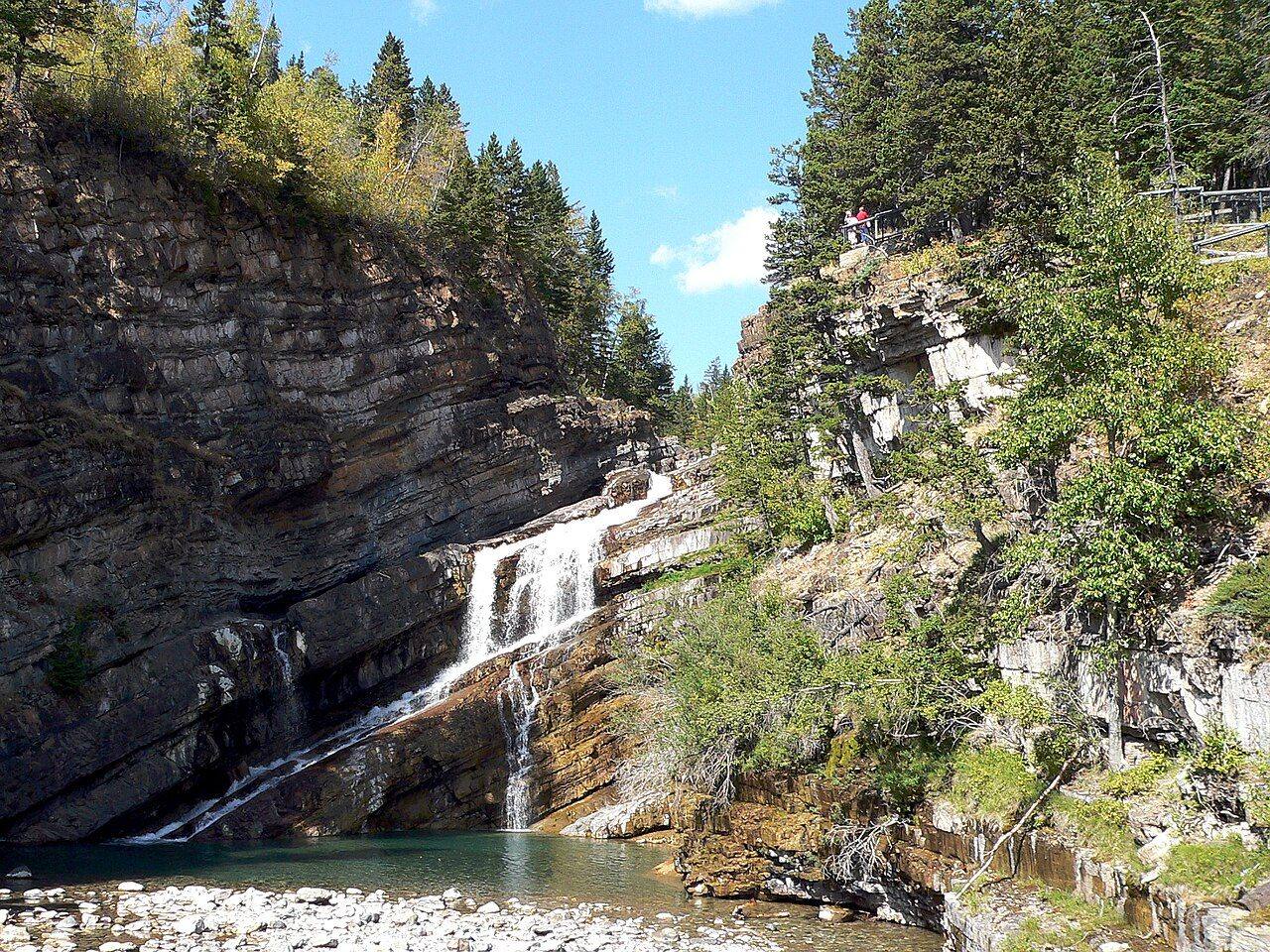 Cameron Falls cascading into a clear pool in Waterton Lakes National Park