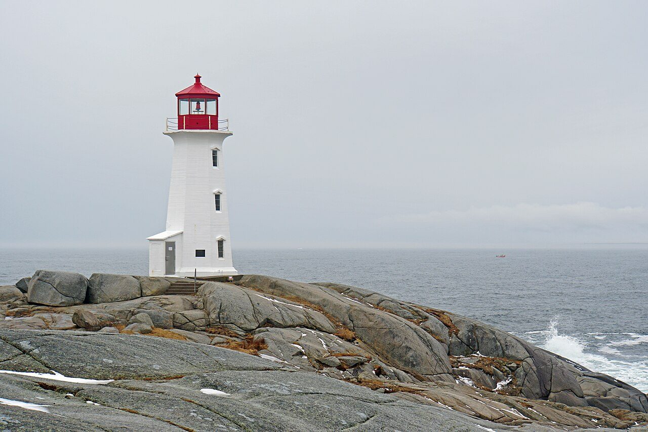 Peggy's Cove lighthouse standing on wave-washed granite rocks above the Atlantic Ocean