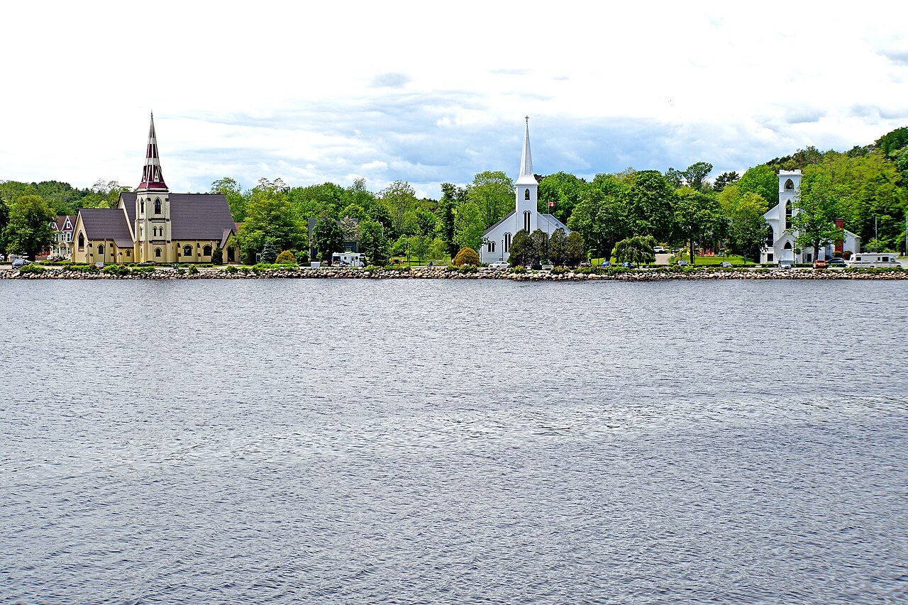 The three historic churches of Mahone Bay seen across the harbour water