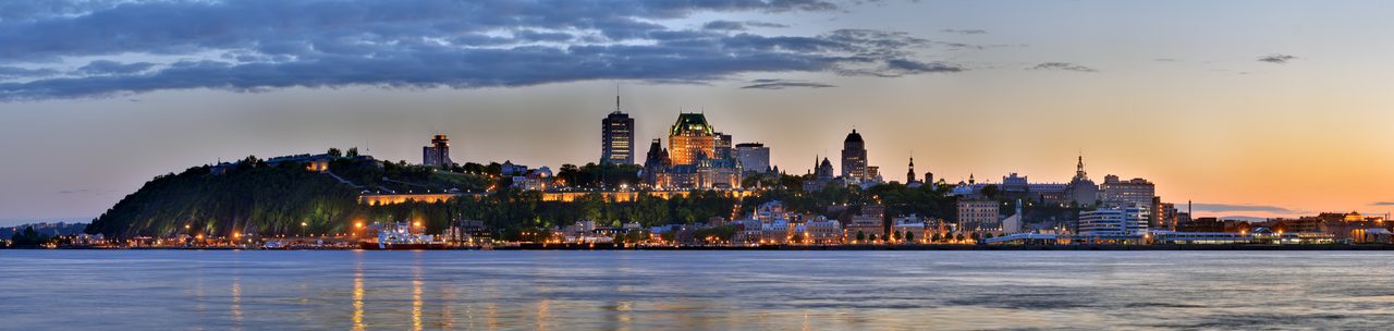 Panoramic dusk view of Québec City's skyline and the Château Frontenac across the St. Lawrence River