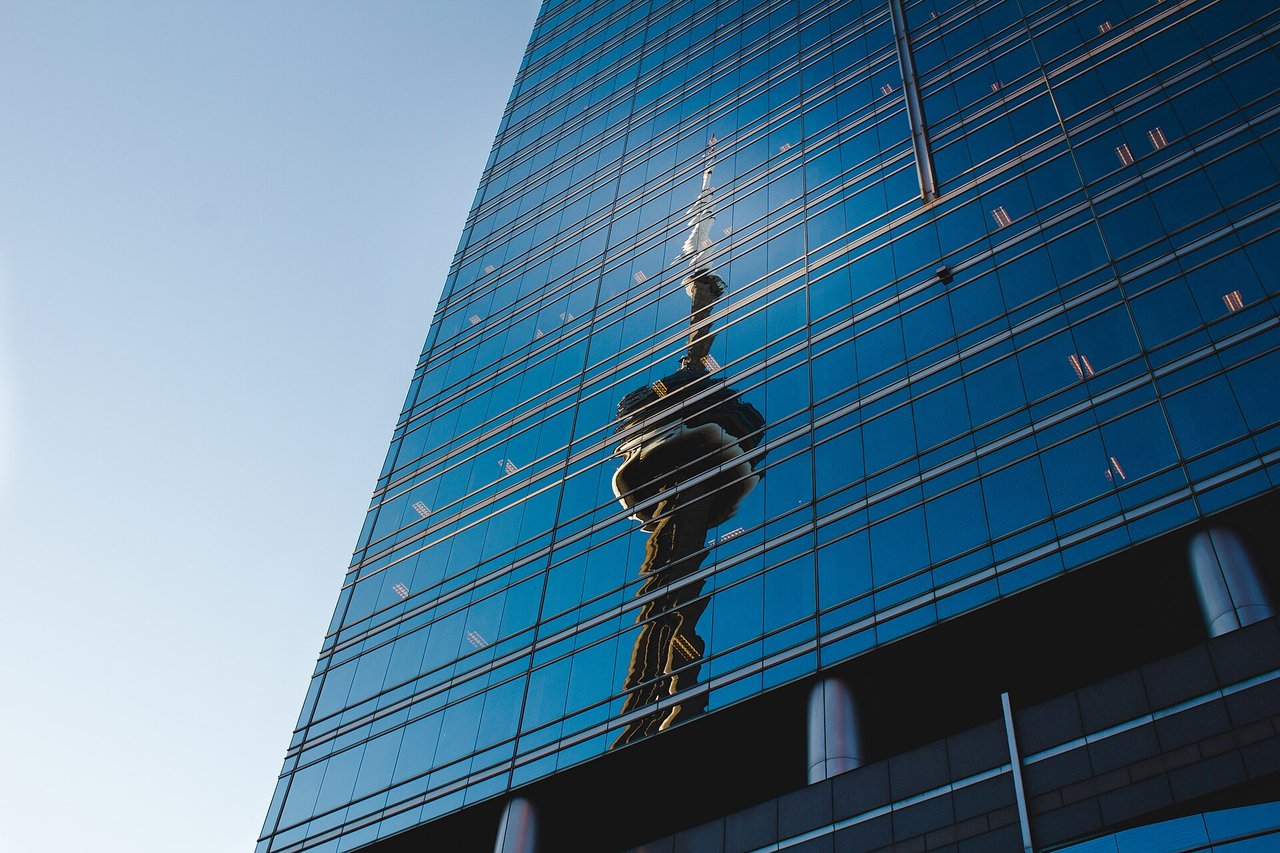 CN Tower rising over downtown Toronto, seen in a glass reflection