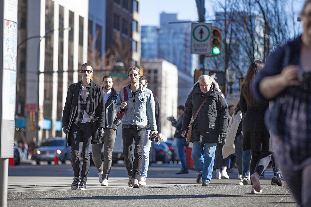 Pedestrians crossing a busy downtown Vancouver street on a sunny day