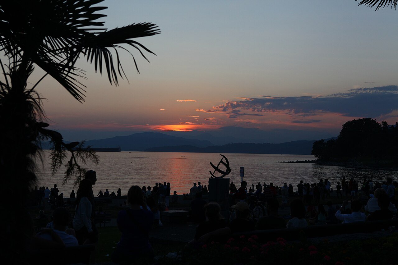 A crowd watching the sunset over English Bay from the West End seawall in Vancouver