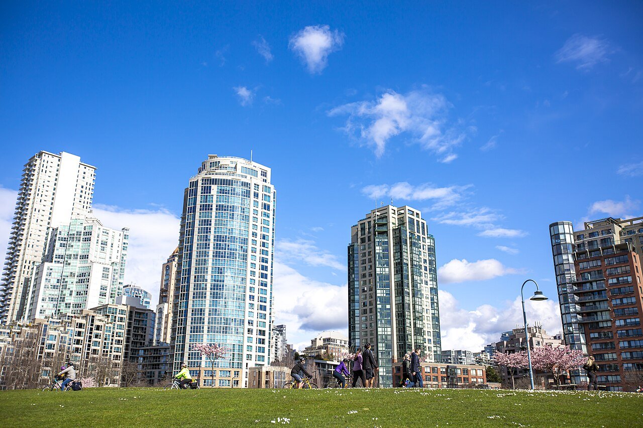 People relaxing in David Lam Park with Yaletown condo towers behind in Vancouver