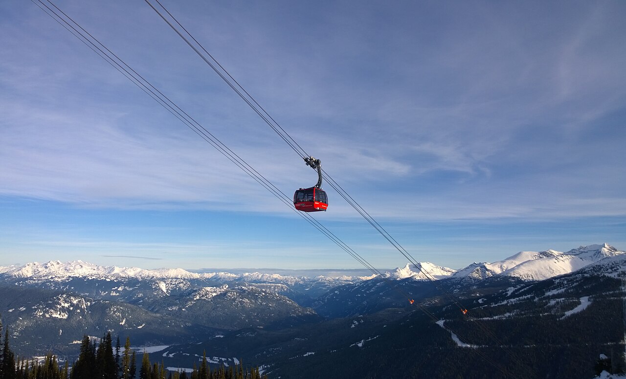 Red PEAK 2 PEAK gondola cabin crossing high above snowy Coast Mountain peaks